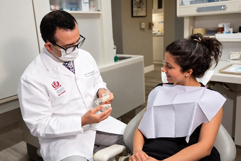 Dr. Pooya explaining a treatment model to a smiling patient